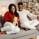 Portrait of happy black couple holding gift and sitting on a coach - PhotoDune Item for Sale
