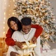 Portrait of happy black couple holding gifts and sitting near Christmas tree - PhotoDune Item for Sale