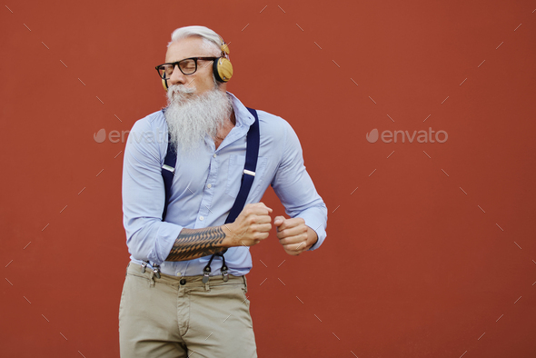 Caucasian hipster happy old man dances listening to music in the city - Seniors enjoy technology