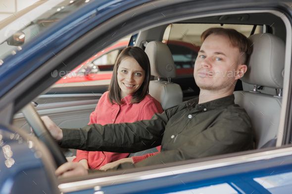 man and a woman couple in a car dealership buy or trade in. car rental or repair service. happy and