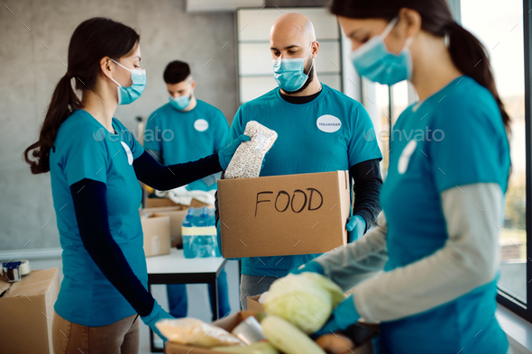 Group of people working in charitable foundation and packing food in donation boxes.