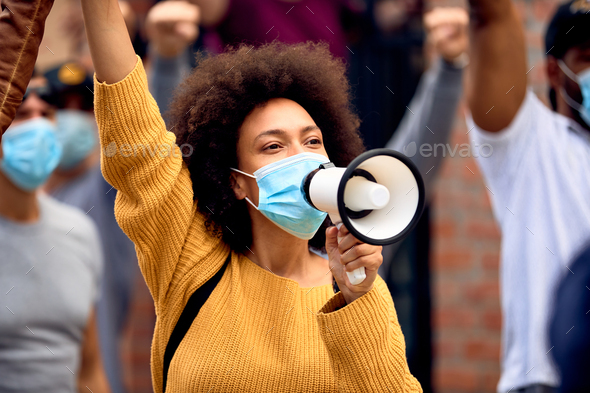Black female activist wearing protective face mask while shouting through megaphone on a protest. - Stock Photo - Images