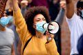 Black female activist wearing protective face mask while shouting through megaphone on a protest. - PhotoDune Item for Sale
