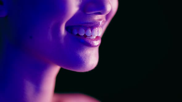 Closeup Shot Of Young Woman's Smile Illuminated With Colorful Neon Light alt