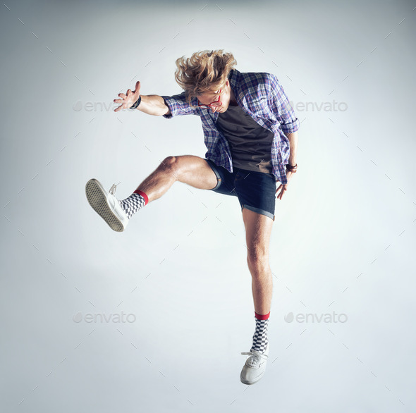 Crazy dance moves. A handsome young man dancing against a gray background.
