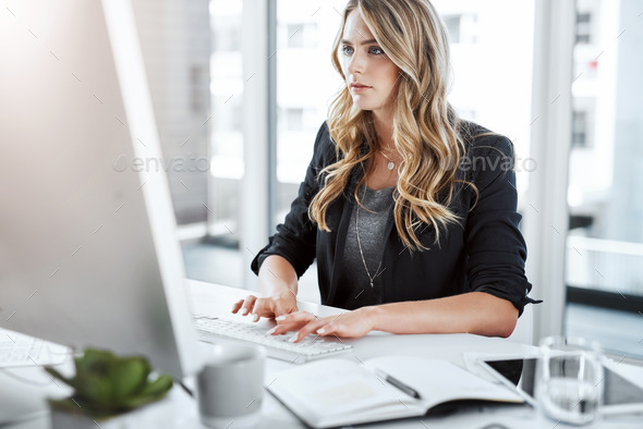 Shot of a young businesswoman using a computer at her desk in a modern ...