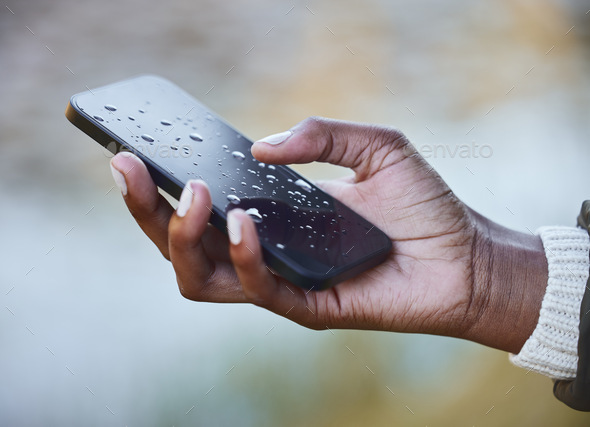 Water damage is so costly to repair. Shot of a woman holding a wet phone during a camping trip.