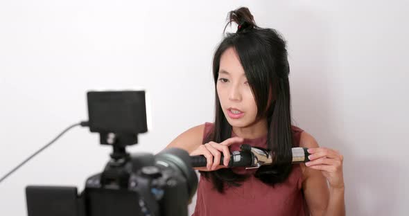 Woman making hair with using hair curler in front of the camera at home alt