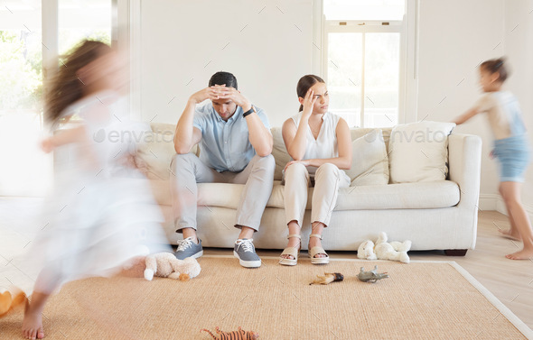 Shot of a young couple looking frustrated while their two daughters play around them