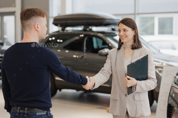 man buys a car at a car dealership. A female salesperson and car rental helps with the purchase - Stock Photo - Images