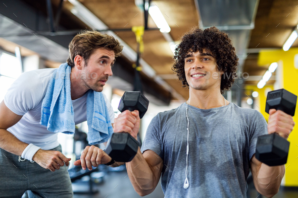 Fitness, sport, exercising concept. Fit man exercising together with his personal trainer in gym. - Stock Photo - Images