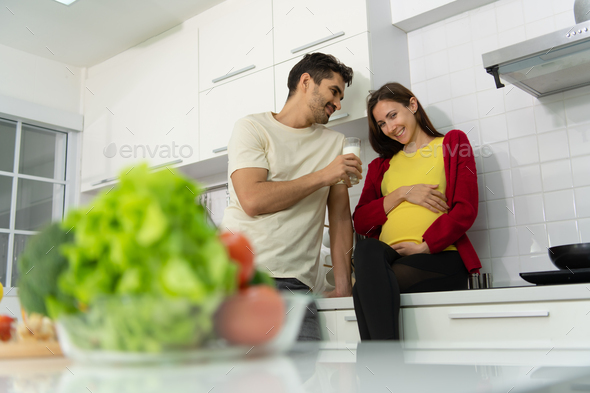 Pregnant woman in kitchen with the atmosphere of cooking with the husband to eat together