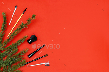 Christmas beauty cosmetics composition, new year decorations on red background.