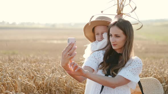 Mother and Daughter Taking Selfie in Wheat Field alt