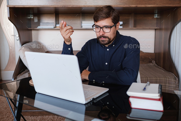 Focused man sitting at desk watching webinar video course