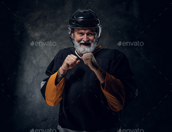 Joyful elderly hockey player posing in combative posture