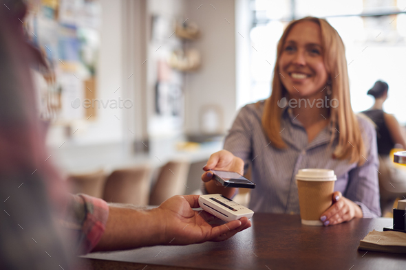 Female Customer Making Contactless Payment In Coffee Shop Using Mobile Phone - Stock Photo - Images