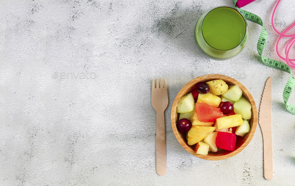 Fruit salad and smoothies on a concrete table.