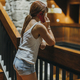 vertical photo of a woman talking on her cell phone on the wooden stairs of a hotel - PhotoDune Item for Sale