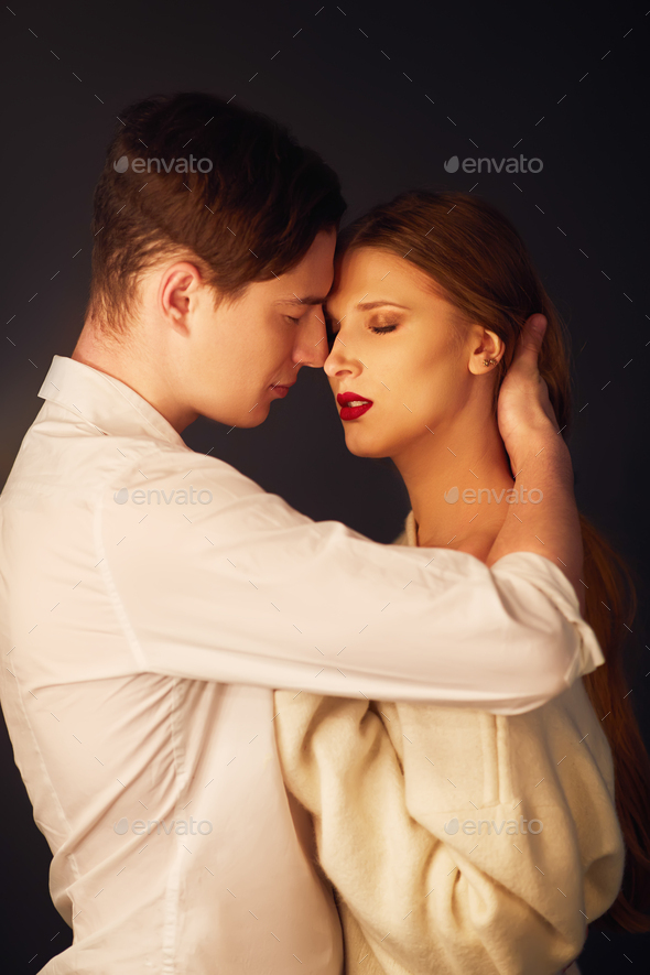Side view of loving young couple kissing on mouth against sky stock photo