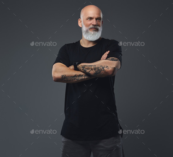 Strong senior man with tattooed hands against gray background - Stock Photo - Images