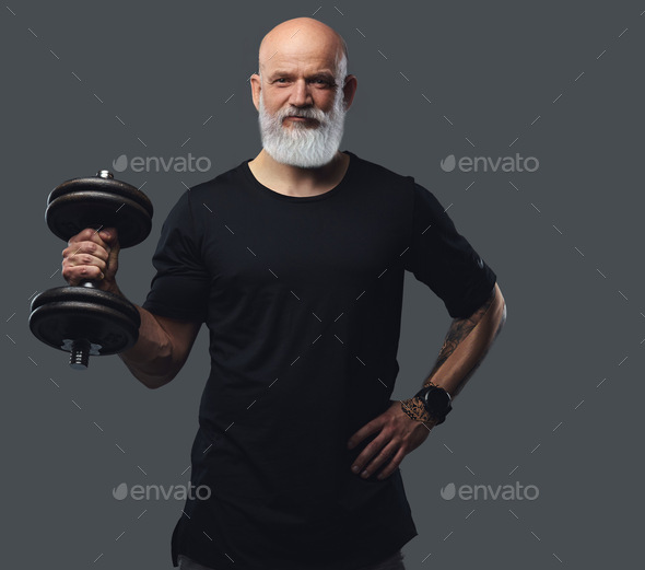 Elderly athlete with dumbell posing against grey background - Stock Photo - Images