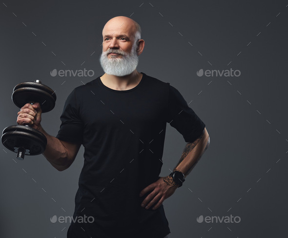 Strong elderly man with dumbell posing against grey background - Stock Photo - Images
