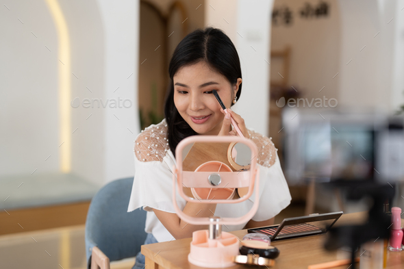 Asian female beauty blogger live streaming to review makeup product on social media, Modern young