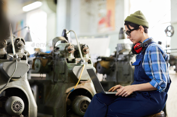Busy watch factory worker using laptop in workshop
