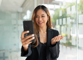 Asian business woman waving fists, got good news on mobile smart phone in office, social media