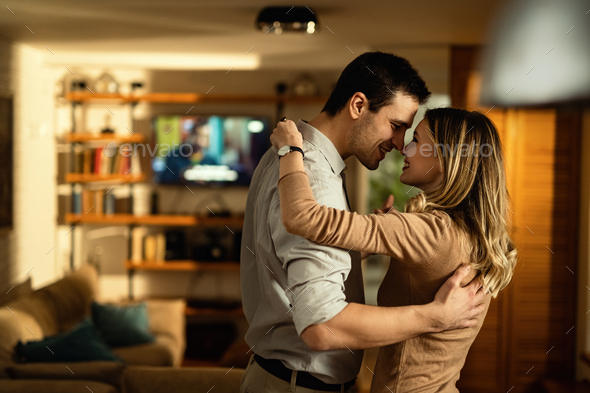 Young romantic couple dancing in the living room.