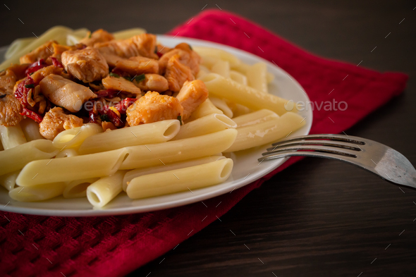 Penne pasta with chicken and vegetables in tomato sauce Stock Photo by