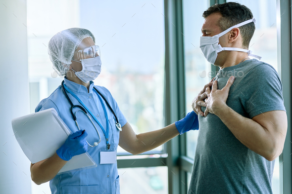 Female doctor talking to patient who is complaining of chest pain at medical clinic.