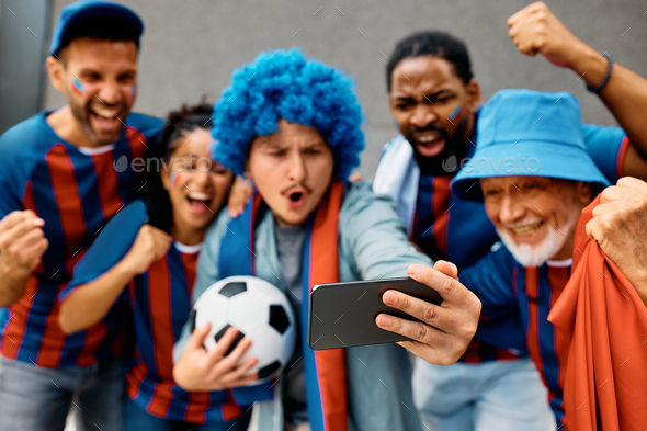 Close up of soccer fans watching a game on smart phone.