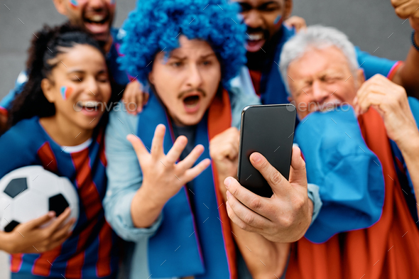 Close up of sports fans watching soccer match on mobile phone.