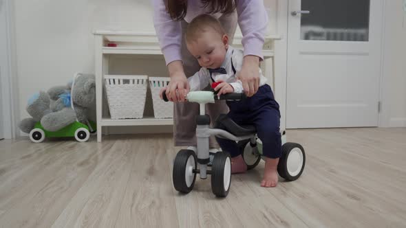 Mother and Baby Boy Play on the Floor Mother Teaches 1 Year Old Child to Ride a Balance Bike alt