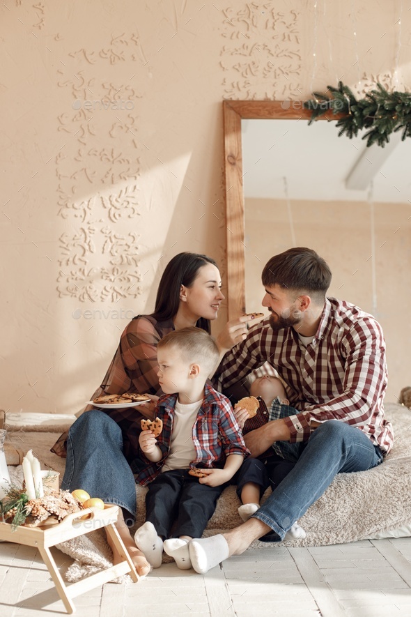 Young family in plaid shirts eating a cookies and hugging - Stock Photo - Images