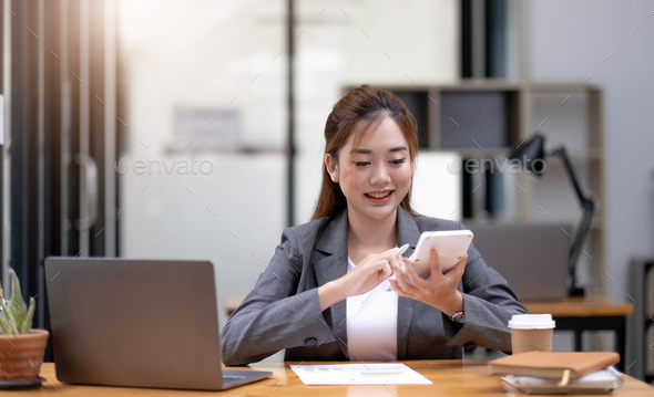 Young Asian businesswoman using a calculator to calculate business principles. Accounting statistics - Stock Photo - Images