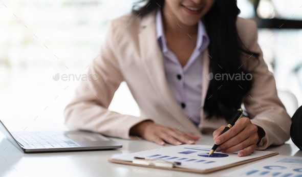 Businesswoman pointing pen at data graph, estimating profit and income statement of business in - Stock Photo - Images