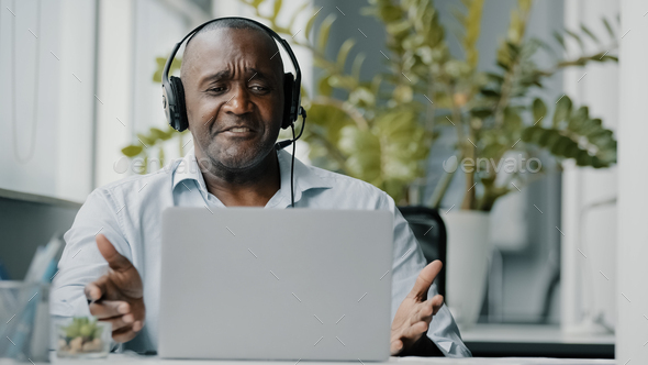 Senior african instructor teacher wears headphones using web camera for communication with clients
