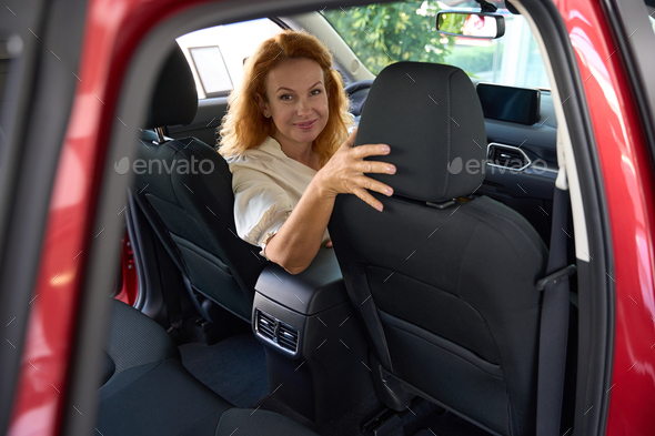 Beautiful woman sits in the driver\'s seat of car half-turned