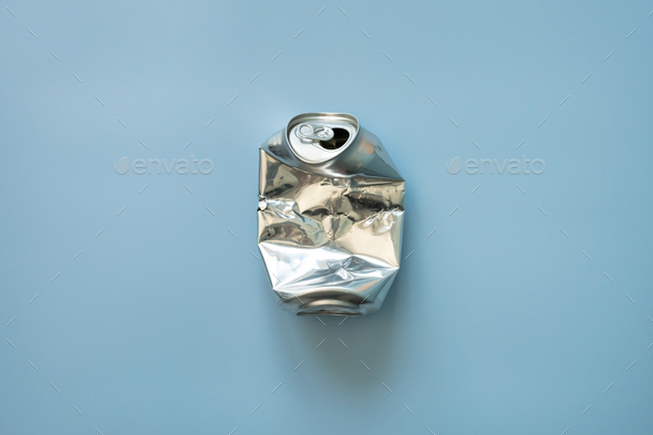 Crumpled aluminum empty soda or beer can, on a blue background. Top view.