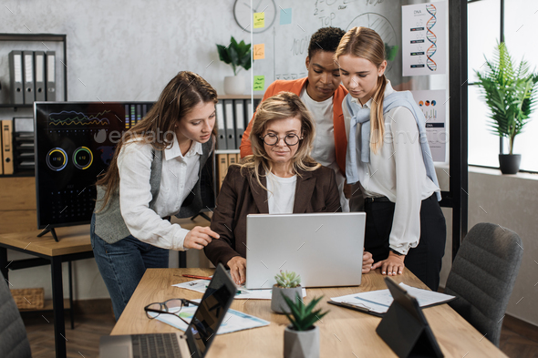 Group of confident high-skilled multiracial business women, standing at the table - Stock Photo - Images