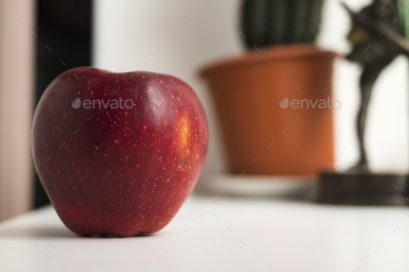 A red delicious apple on a white windowsill.