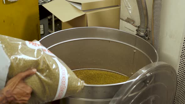Container being filled with plastic vinyl grenules in a music record factory alt