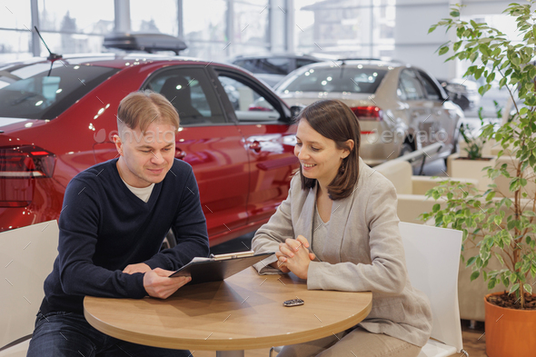 man buys a car at a car dealership. A female salesperson and car rental helps with the purchase - Stock Photo - Images