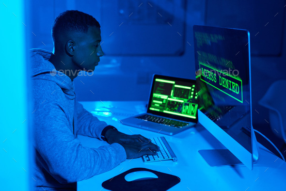 Shot of a young male hacker cracking a computer code in the dark