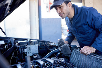 Cropped shot of a handsome young male mechanic working on the engine of a car during a service
