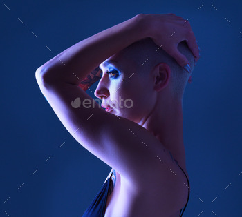 Studio shot of an attractive young woman wearing edgy makeup against a blue background