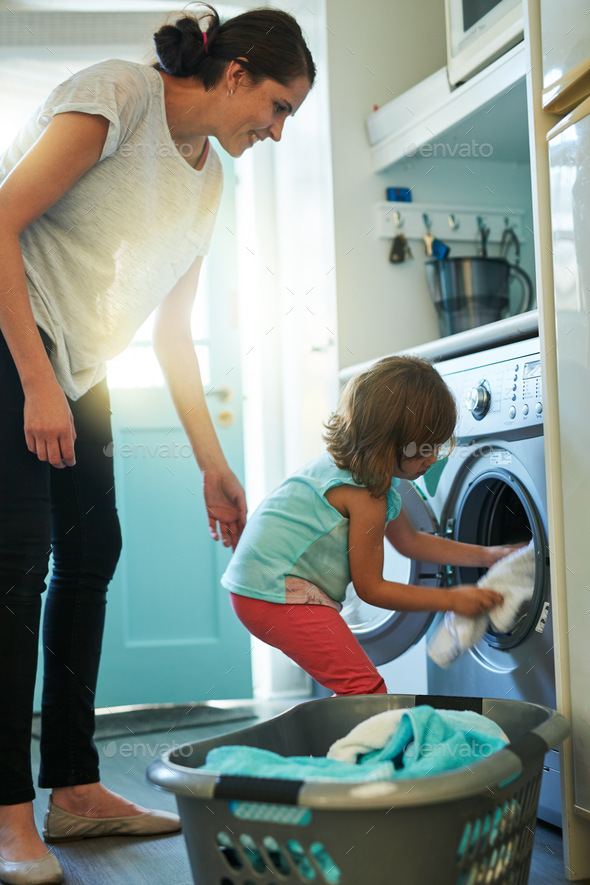 Loading the washing machine. Shot of a mother and daughter using a